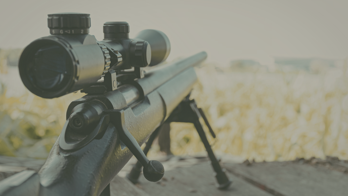Bolt-action rifle with scope resting on a bipod at a shooting range
